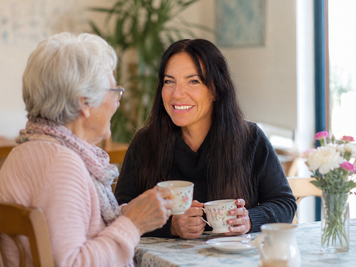 Caring Befriender companion sharing tea and conversation with an older woman